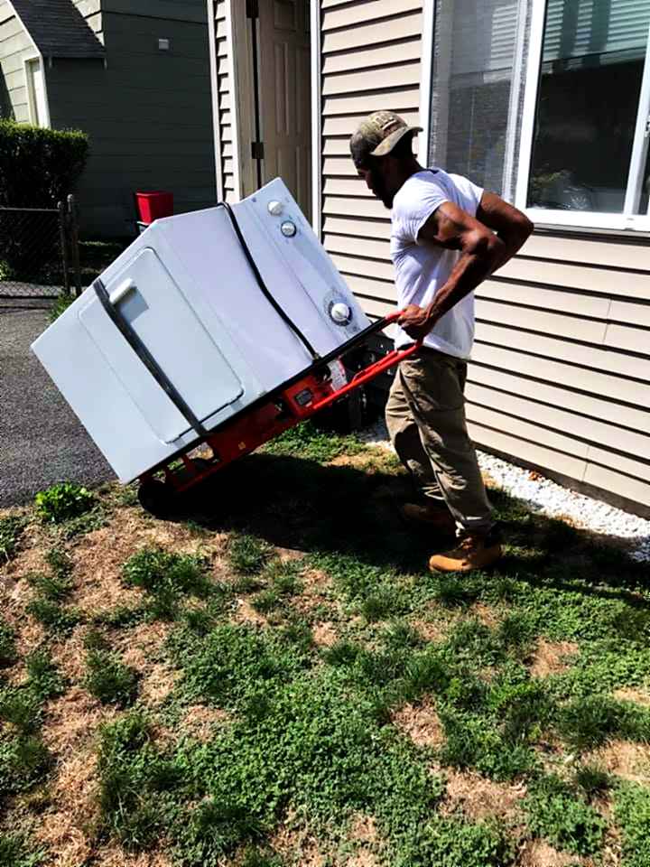 An appliance strapped to the hand truck for the carry across the yard