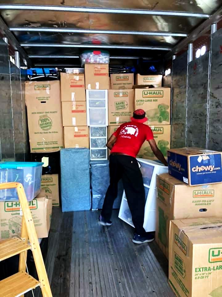 A crew member tiering labelled boxes and totes inside the truck