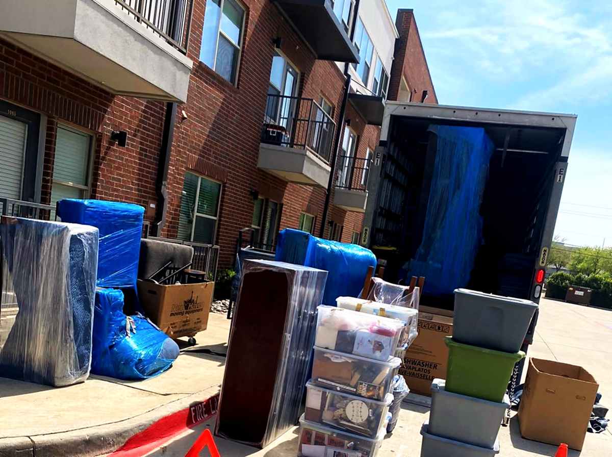 A job in progress — furniture wrapped and staged at the curb beside the open truck
