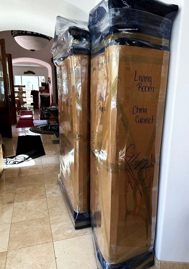 A china cabinet blanket-wrapped, shrink-wrapped and labelled by room
